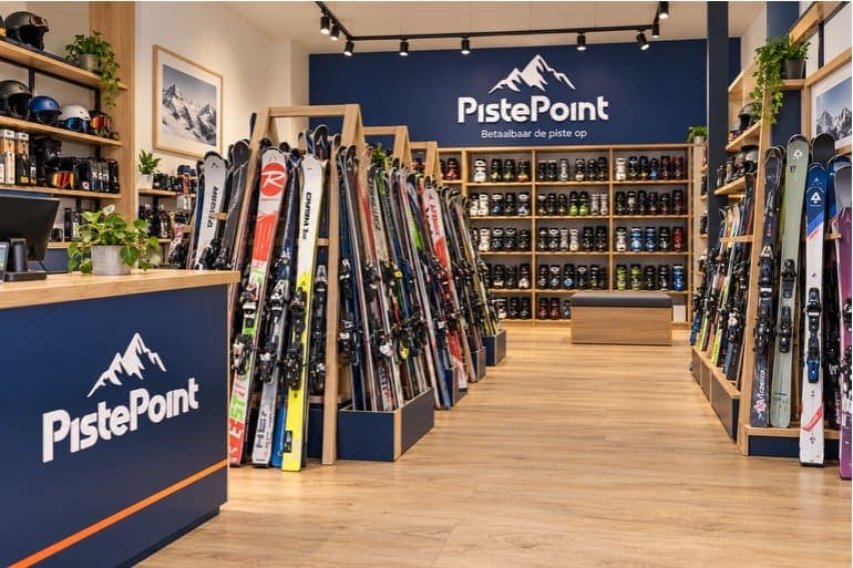 De winkel van PistePoint: rekken met tweedehands ski's en een wand vol skischoenen